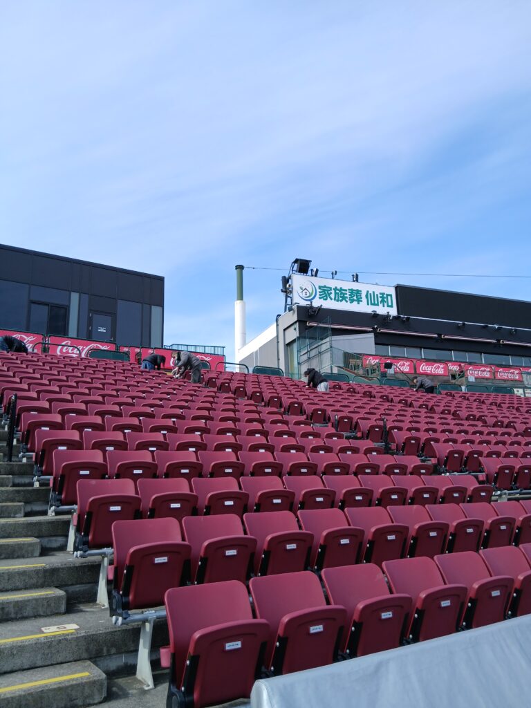 手前に沢山の椅子があり、奥側で掃き掃除をしている写真