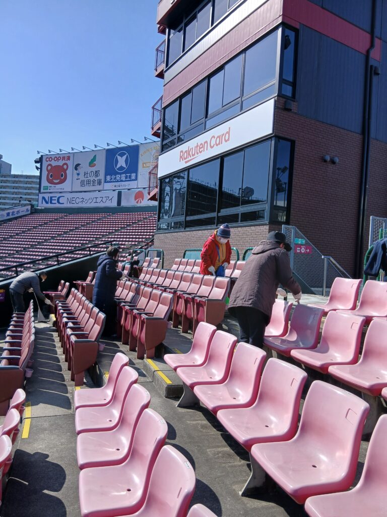 複数人で球場内の掃き掃除をしている写真